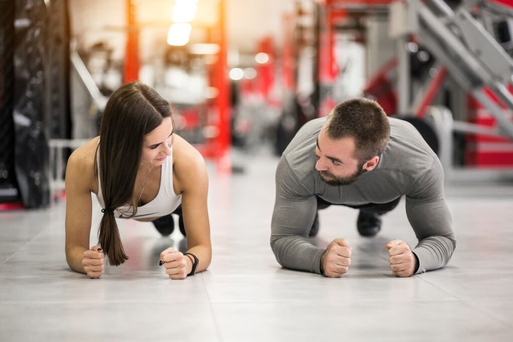 A man and a woman do the Plank exercise, which is designed for all muscle groups